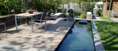 Schroeer Garten- und Landschaftsbau zeigt eine Terrasse mit Tisch und Stühlen und einem Teich